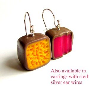 May include: A pair of earrings with a brown, yellow, and pink geometric design. The earrings are made of polymer clay and have silver ear wires. Also available in earrings with sterling silver ear wires.
