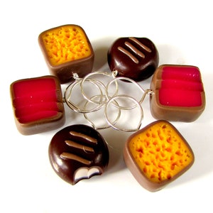 May include: A set of six chocolate and caramel candy charms with a honeycomb pattern, connected by silver rings. The charms are in the shape of squares and rectangles.