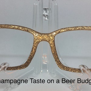 May include: Gold glitter glasses with the text "Champagne Taste on a Beer Budget" printed below.