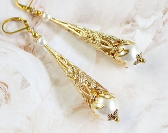 May include: A pair of gold filigree earrings with white pearl accents. The earrings are long and dangle, with a delicate design.