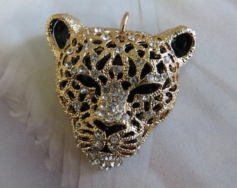 May include: Gold-tone pendant featuring a detailed, jeweled jaguar head design. The pendant has black enamel accents and clear rhinestones.