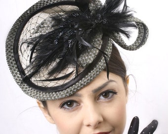 May include: A woman wearing a black and white fascinator with a black feather and a black dress with white polka dots.