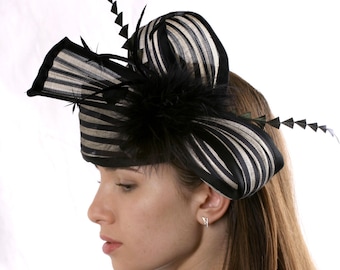 May include: A black and white striped hat with a black feather accent. The hat is worn by a person with long brown hair.