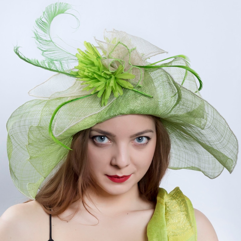 May include: A green and white hat with a large green flower and a feather. The hat is made of a delicate, mesh-like material.