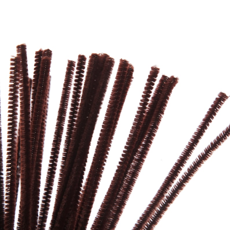 Puede incluir: Primer plano de un grupo de limpiapipas marrones. Estos materiales de manualidades, difusos y texturizados, est&aacute;n dispuestos sobre un fondo blanco. Estos tallos flexibles, con alambre en el centro, se utilizan a menudo en proyectos art&iacute;sticos.