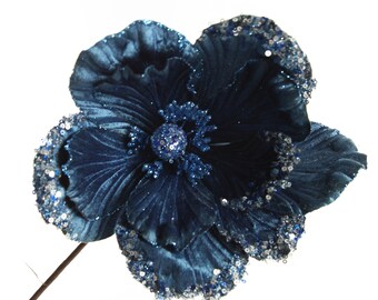Könnte beinhalten: Eine einzelne blaue Samt-Blume mit silbernen Glitzer-Akzenten. Die Blume hat eine gekräuselte Textur und eine Mitte mit einem blauen Glitzer-Verzierungen.