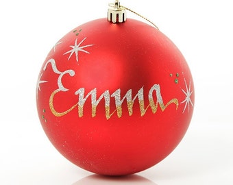 May include: Red Christmas bauble with the name "Emma" written in gold and silver glitter on the front. The bauble is decorated with small white stars.