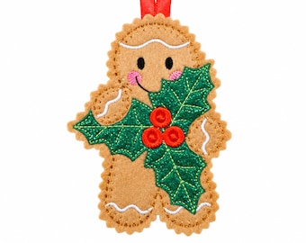 May include: A tan felt gingerbread person ornament with scalloped edges, featuring embroidered black eyes, pink cheeks, and white icing details. A large green glittery holly leaf applique with three red berries covers the center.