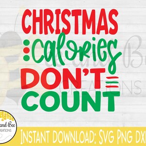 May include: Red and green text on a white wood background reads "Christmas calories don't count".