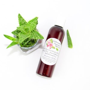 A 4 oz amber bottle of Pure Aloe Vera product, enriched and authentic, surrounded by fresh aloe vera leaf pieces, showcasing the natural ingredients and the premium quality of the product.