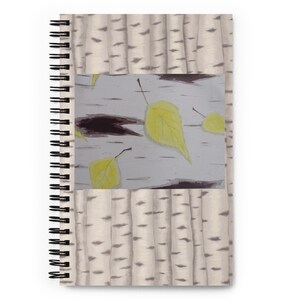 May include: A spiral bound notebook with a white background featuring a pattern of brown birch tree bark. The cover has a rectangular image of yellow leaves falling against a white background with brown birch tree bark.
