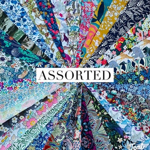 May include: A collection of assorted fabric swatches, each with a unique floral or patterned design. The fabrics are arranged in a fan shape, showcasing a variety of colors including blue, pink, yellow, and green. The word "ASSORTED" is displayed in a white rectangle.
