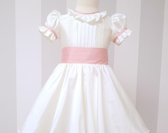 Robe de cérémonie fille modèle Pippa, mariage royal. De couleur IVOIRE avec des décorations roses. Robe de mariée fille avec gros noeud