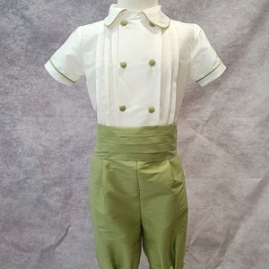 May include: A white short-sleeved shirt with green trim and a green sash, paired with green shorts. The outfit is displayed on a white mannequin.
