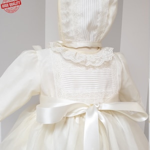Peut inclure: Une robe de bapt&ecirc;me blanche avec une bordure en dentelle et un n&oelig;ud en satin. La robe a des manches longues et une jupe ample. La robe est faite d'un tissu de haute qualit&eacute; et est parfaite pour une occasion sp&eacute;ciale.
