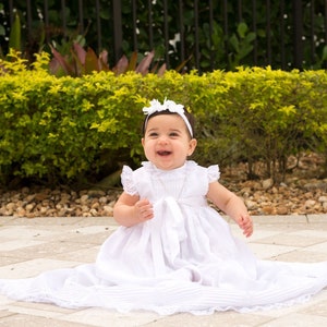 Baptism dress for babies made in white linen with laces handicraft. Top and bottom with white laces. Unisex. Christening baby dress in white