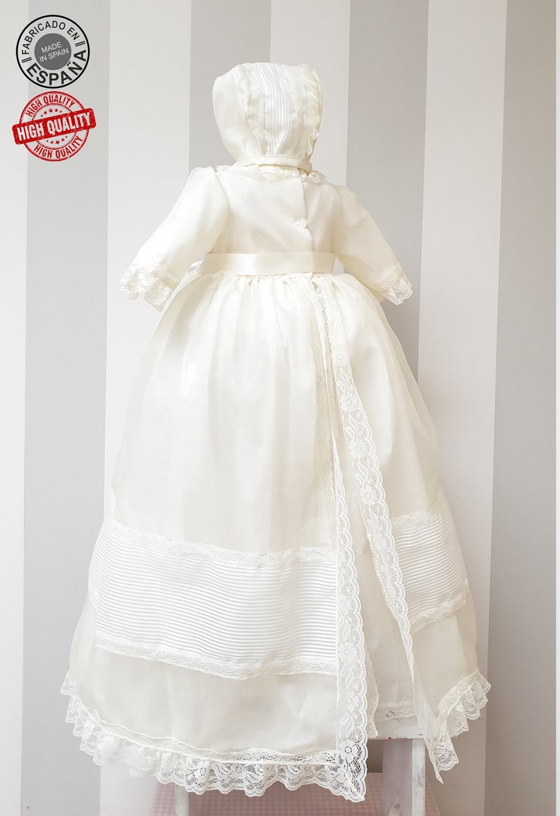 Peut inclure: Une robe de bapt&ecirc;me blanche avec une bordure en dentelle et une ceinture en satin. La robe est assortie &agrave; un bonnet.