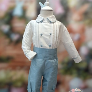 May include: A white button-up shirt with blue trim and a blue sash, paired with blue shorts. The outfit is on a white mannequin.