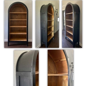 K&ouml;nnte beinhalten: Ein schwarzes, gew&ouml;lbtes B&uuml;cherregal mit vier Regalbrettern. Die Regalbretter sind aus Holz und in einem hellen Braunton gebeizt. Das B&uuml;cherregal steht auf einem Holzboden.