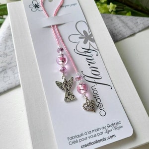 Peut inclure: Marque-page à perles roses avec un ange et un cœur en argent. Le marque-page est fait à la main au Québec, Canada. "Création Floraly" est imprimé sur la carte.
