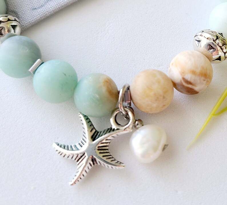 May include: A bracelet with light blue and brown beads, a silver starfish charm, and a white pearl charm.