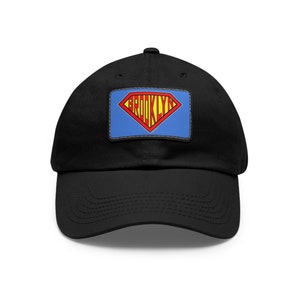 May include: Black baseball cap with a blue and red Superman logo patch that says "BROOKLYN" in yellow letters.