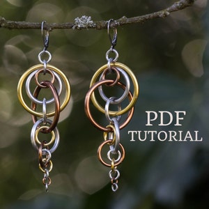 Puede incluir: Un par de pendientes de plata, oro y cobre con un diseño de cadena. Los pendientes están colgados de una rama. El texto "PDF TUTORIAL" es visible en la imagen.