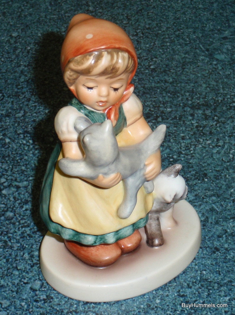 Puede incluir: Una figurita de porcelana de una ni&ntilde;a con un vestido rojo y verde que sostiene dos gatitos. La ni&ntilde;a tiene el pelo rubio y lleva una capucha roja. Los gatitos son grises y blancos.