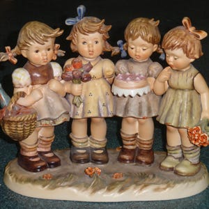 Könnte beinhalten: Vier Porzellanfiguren von Mädchen in Vintage-Kleidern. Die Mädchen halten einen Kuchen, Blumen und einen Korb. Die Figuren stehen auf einem Sockel mit Blumenmuster.