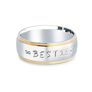 May include: A silver and gold ring with the word "BESTIES" engraved on it.