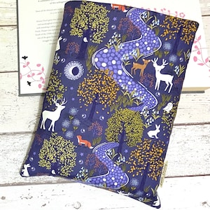 May include: A dark blue book cover featuring a whimsical forest scene. The cover depicts a winding path, trees, deer, a fox, and a rabbit. The text "Book Buddy" is printed in white on the bottom right corner.