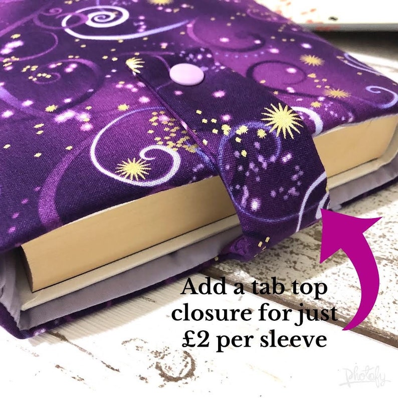 May include: A purple book sleeve with a celestial design featuring swirling patterns and starbursts. The sleeve has a tab closure with a light purple button. The text "Add a tab top closure for just" is visible.