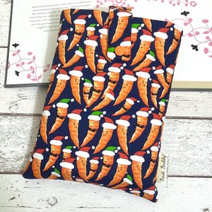 May include: A blue book cover with a repeating pattern of carrots wearing Santa hats and bow ties. The text "Book Buddy" is printed on the bottom right corner of the cover.