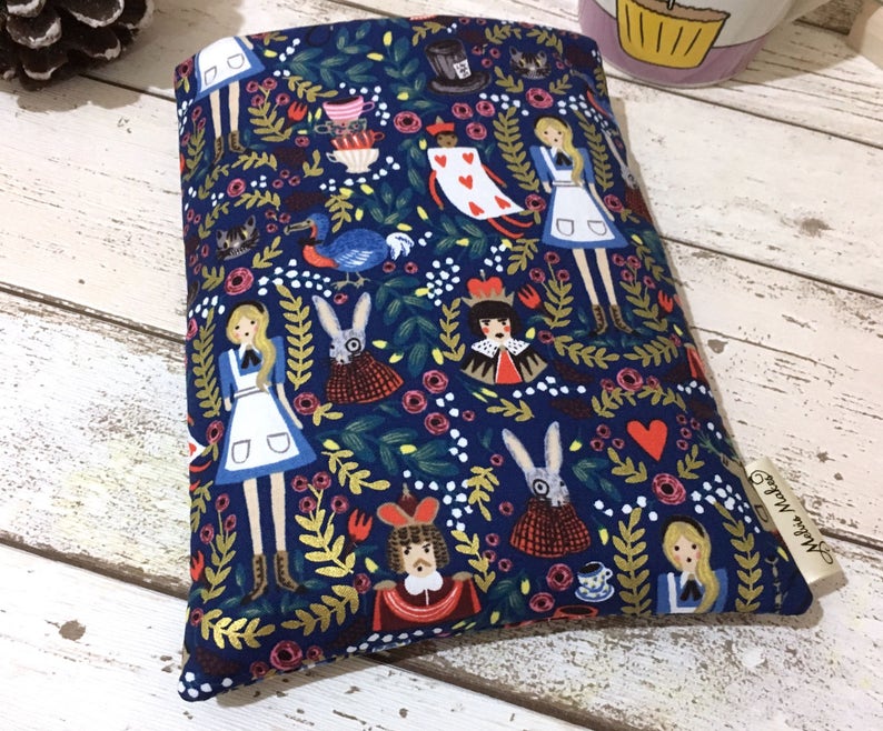 May include: A rectangular fabric pouch featuring a dark blue background with a repeating pattern of Alice in Wonderland characters, including Alice, the White Rabbit, the Queen of Hearts, and the Dodo, surrounded by floral elements and hearts.
