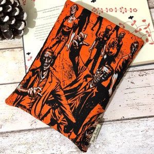 May include: Orange and black book cover featuring a graphic print of zombies. The cover has the text "Book Buddies" printed on the bottom right corner.