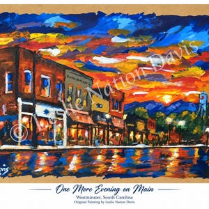 May include: An acrylic painting titled One More Evening on Main, Westminster, South Carolina by Leslie Nation Davis. It depicts a downtown street scene at sunset with vibrant orange, red, and blue skies reflecting on a wet, dark street surface.