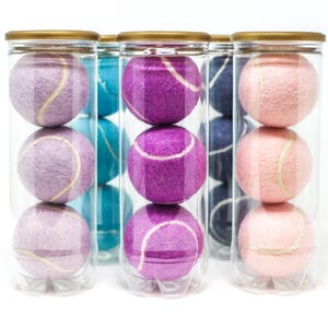 Pastelkleurige tube tennisballen, in roze, blauw en paars