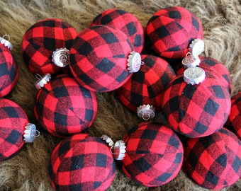 May include: A collection of red and black plaid Christmas ornaments. The ornaments are round and have a shiny silver top.