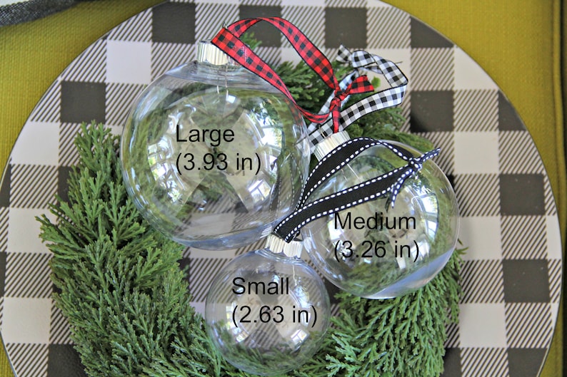 May include: Three clear glass Christmas ornaments of different sizes with black and white ribbon. The ornaments are labeled "Large (3.93 in)", "Medium (3.26 in)", and "Small (2.63 in)".