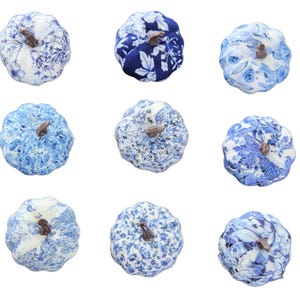 Pode incluir: Uma cole&ccedil;&atilde;o de nove ab&oacute;boras de tecido dispostas numa grelha, cada uma com padr&otilde;es florais ou bot&acirc;nicos distintos em azul e branco. Cada ab&oacute;bora &eacute; rematada com um pequeno caule castanho texturado, exibindo v&aacute;rios tons de azul e branco.
