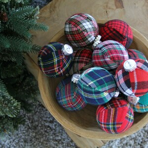 May include: A bowl filled with plaid fabric Christmas ornaments in red, green, blue, and white.
