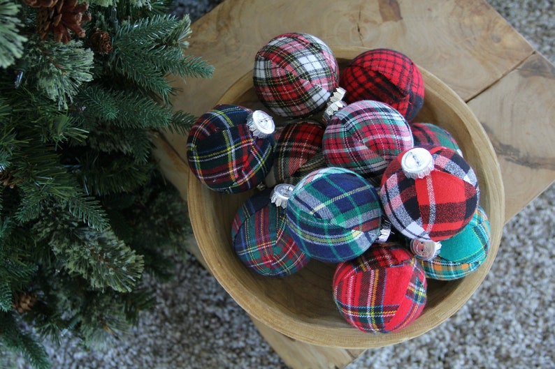 May include: A bowl filled with plaid fabric Christmas ornaments in red, green, blue, and white.