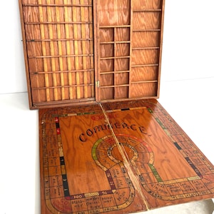 May include: A white ceramic mug with a black handle and the text "But First, Coffee" in a bold, black font. The mug is set against a blurred background, suggesting a cozy setting. The mug appears to be approximately 4 inches tall.