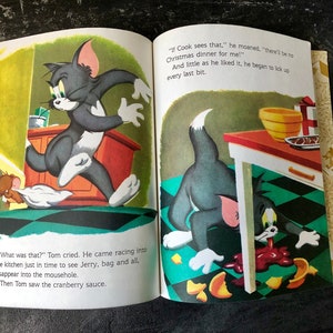 May include: Tom and Jerry cartoon illustration from a children's book. Tom is running away from Jerry, who is hiding in a mousehole. Tom is licking up cranberry sauce that has spilled on the floor. The text reads "What was that?" Tom cried. He came racing into the kitchen just in time to see Jerry, bag and all, disappear into the mousehole. Then Tom saw the cranberry sauce. "If Cook sees that," he moaned, "there'll be no Christmas dinner for me!" And little as he liked it, he began to lick up every last bit.