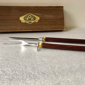May include: A set of two carving tools with brown and yellow striped handles in a wooden box with the text "The Connoisseurs Choice" on the lid.