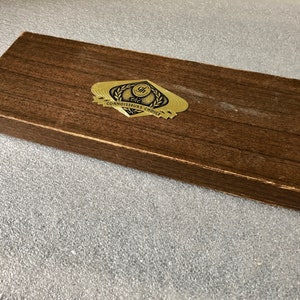 May include: A brown wooden box with a gold label that reads "The Connoisseurs Choice".