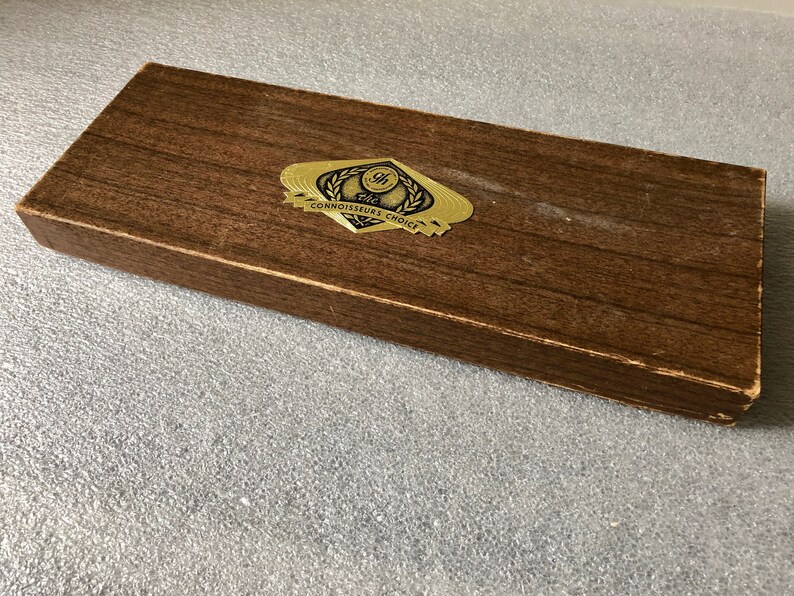 May include: A brown wooden box with a gold label that reads "The Connoisseurs Choice".