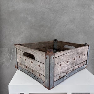 Peut inclure: Une caisse en bois vintage avec des accents métalliques. La caisse a une poignée sur le dessus et les mots "The Farmers Co-operative" sont imprimés sur le côté. La caisse est patinée et a un aspect rustique.