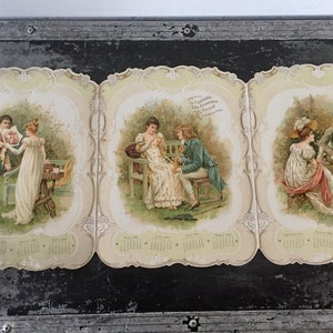 Puede incluir: Tres tarjetas de calendario vintage con escenas románticas de parejas en un entorno de jardín. Cada tarjeta tiene una escena diferente e incluye un calendario para el año 1917.