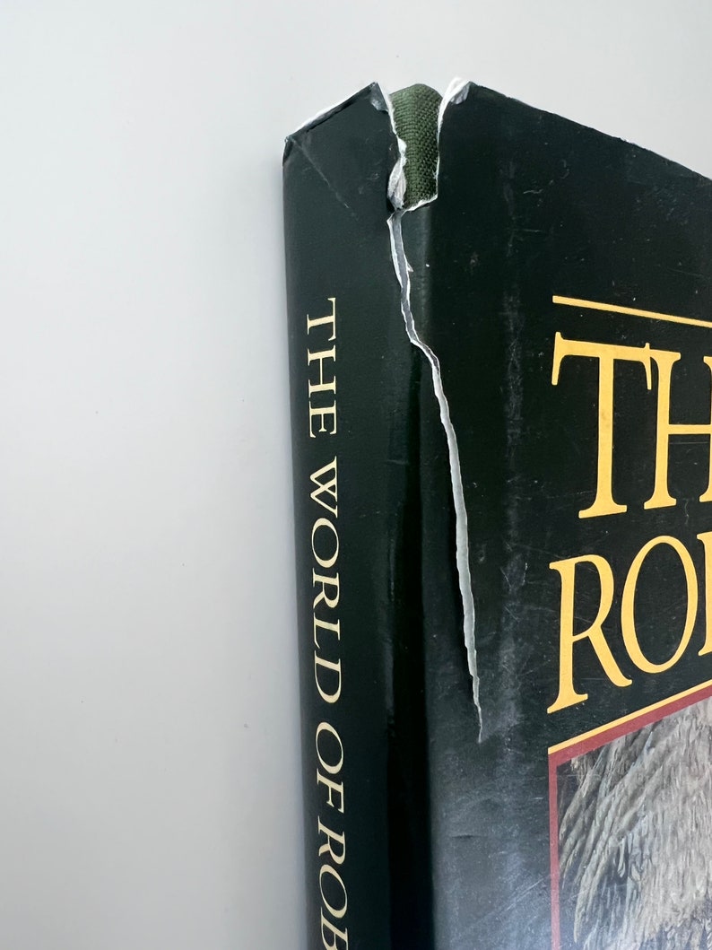 May include: A black hardcover book with gold lettering on the spine that reads "The World of Robin", and gold lettering on the front cover that reads "The World of Robin".